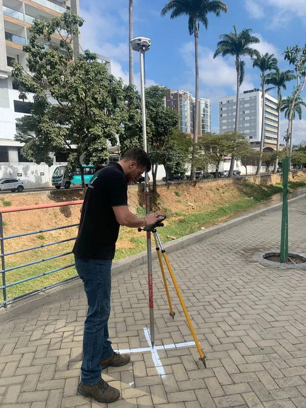 Aloísio Sartori em campo, com o receptor GPS montado no tripé sobre um ponto marcado na calçada